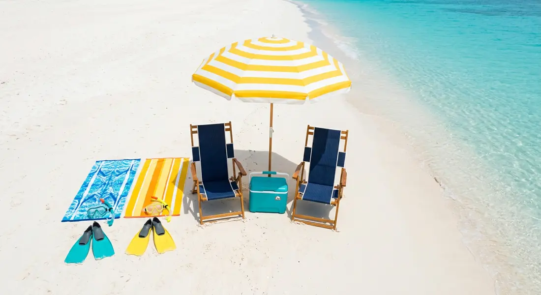 Folding beach chairs, cooler, sun umbrella and snorkel gear on the sand